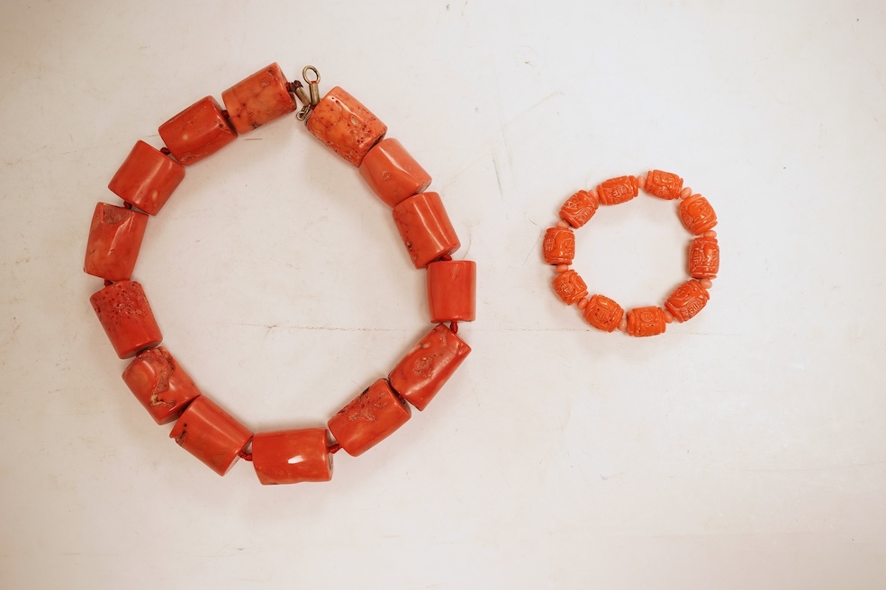 Two coral bead necklaces, one composed of large cylindrical coral beads, approximately 2.5-3.5cm each, total length 49cm; and a bracelet composed of carved coral beads spaced by smaller pink coral beads, on an elasticate